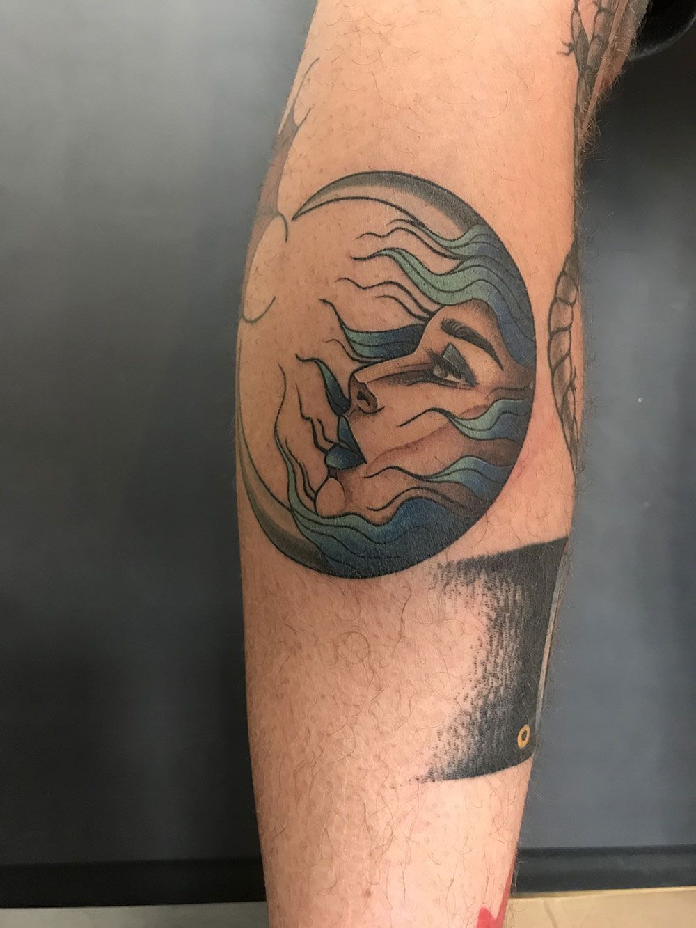 Ein Mann hat ein Tattoo mit dem Gesicht einer Frau auf seinem Bein.