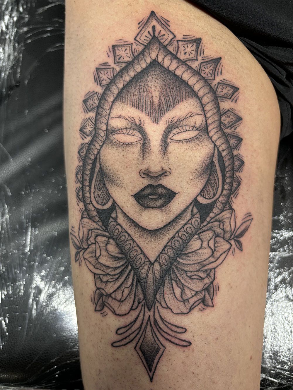 Ein schwarz-weißes Tattoo eines Frauengesichts mit geschlossenen Augen