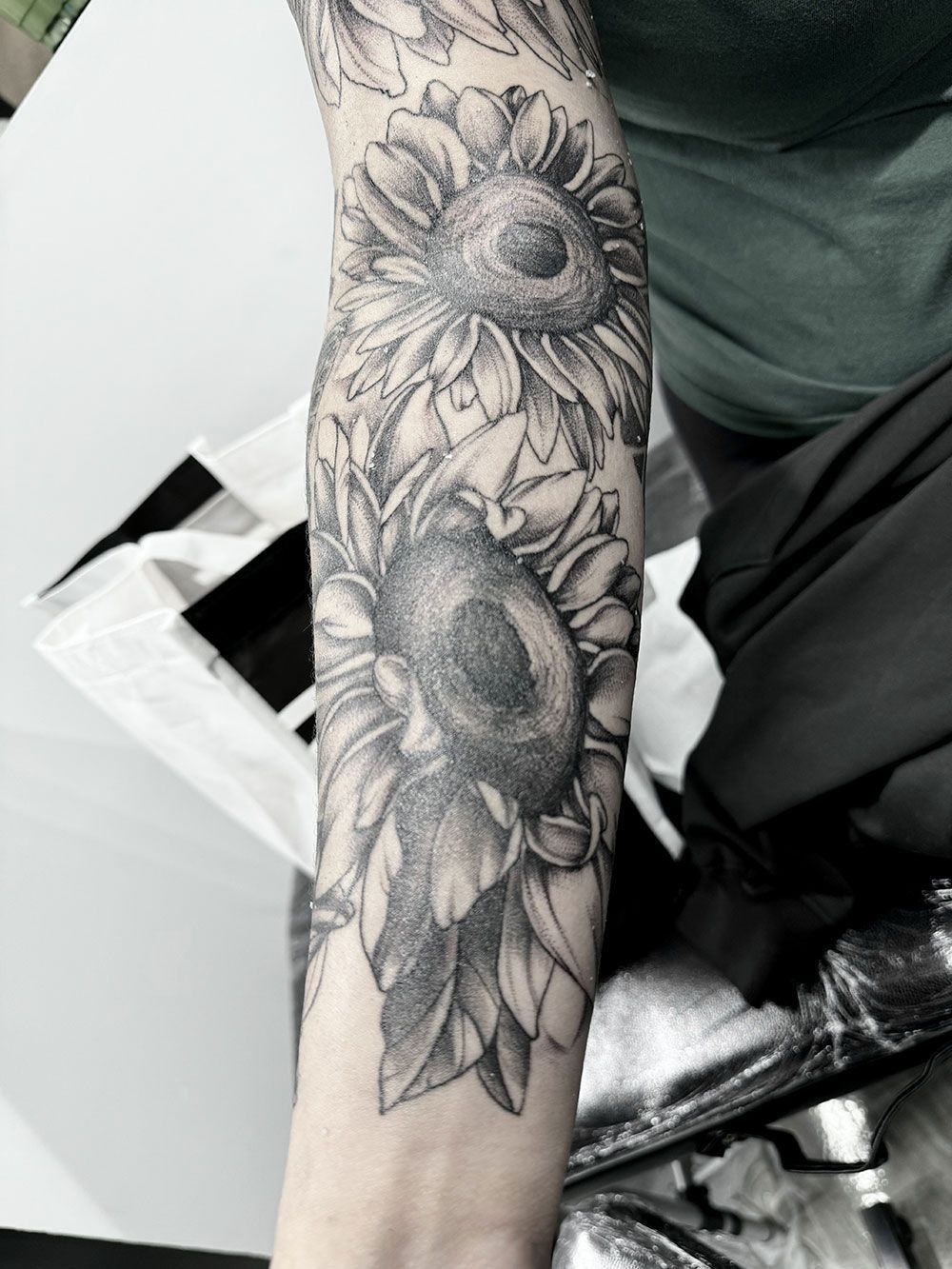 Eine Frau hat eine Tätowierung mit Sonnenblumen auf ihrem Arm