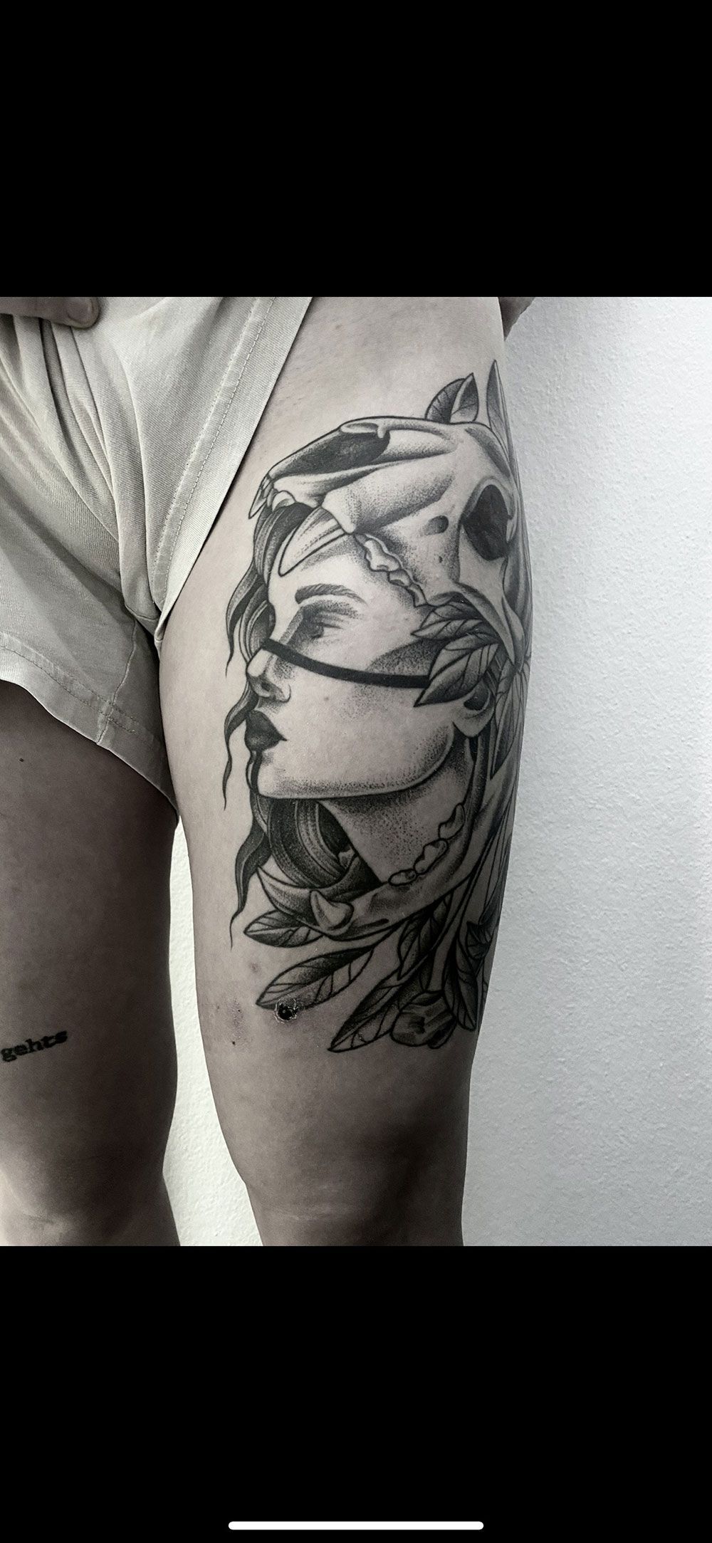 Ein Schwarzweißfoto einer Tätowierung auf dem Bein einer Frau.