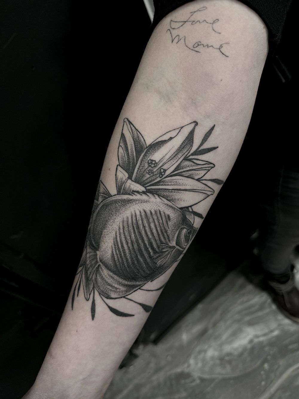 Eine Person hat eine Blumentätowierung auf dem Unterarm.