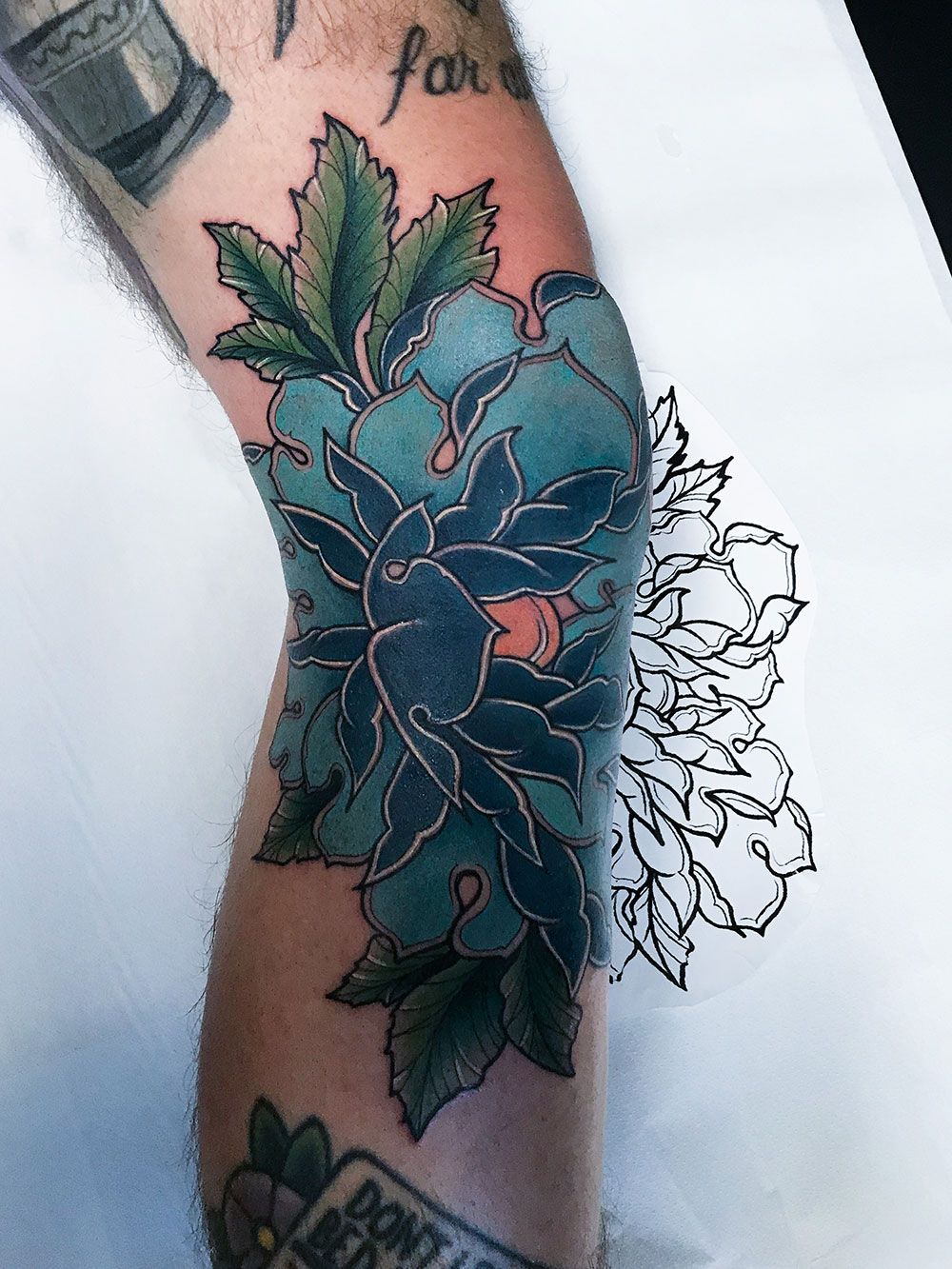 Eine Person hat eine Tätowierung einer blauen Blume auf ihrem Ellbogen