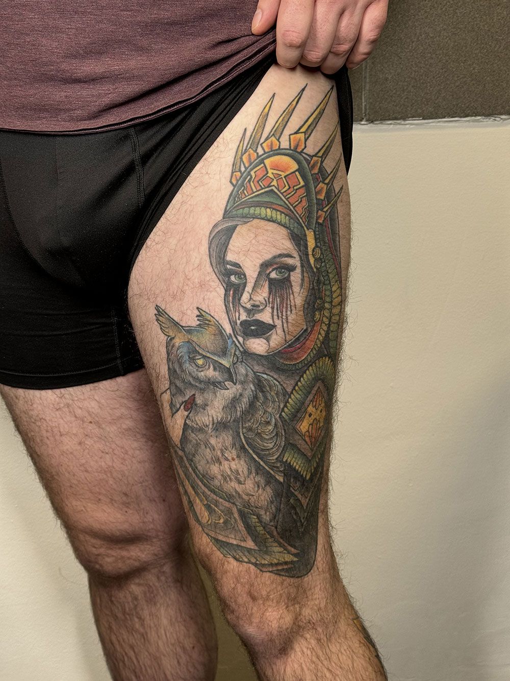 Ein Mann hat auf seinem Oberschenkel eine Tätowierung einer Frau mit einer Krone.