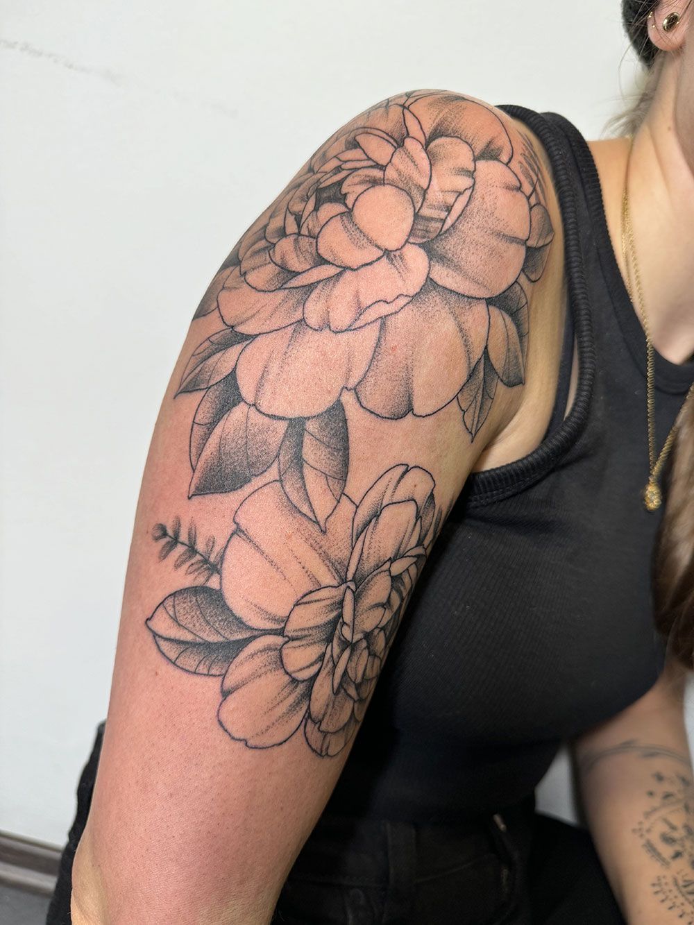 Eine Frau hat eine Blumentätowierung auf ihrer Schulter.