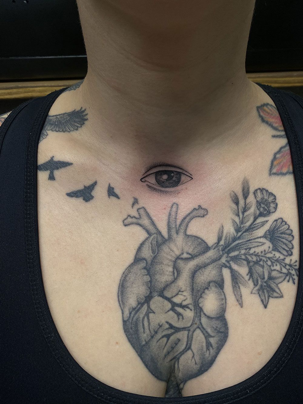 Eine Frau hat ein Tattoo mit einem Herzen und einem Auge auf ihrer Brust