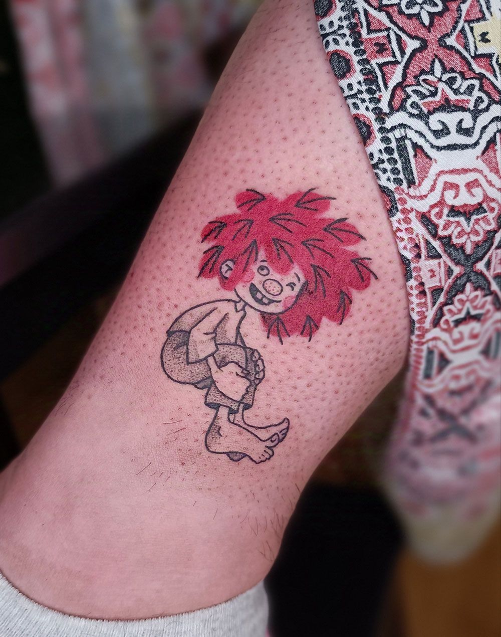 Eine Person hat eine Clown-Tätowierung auf dem Bein.