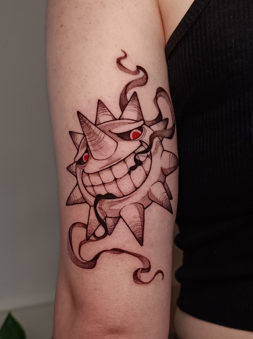 Eine Frau hat eine Tätowierung einer lächelnden Sonne auf ihrem Arm