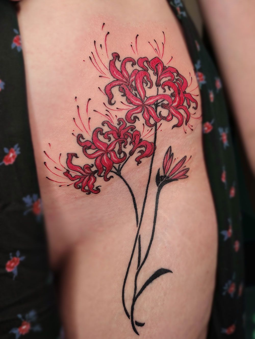 Eine Frau hat eine Tätowierung mit roten Blumen auf ihrem Arm.