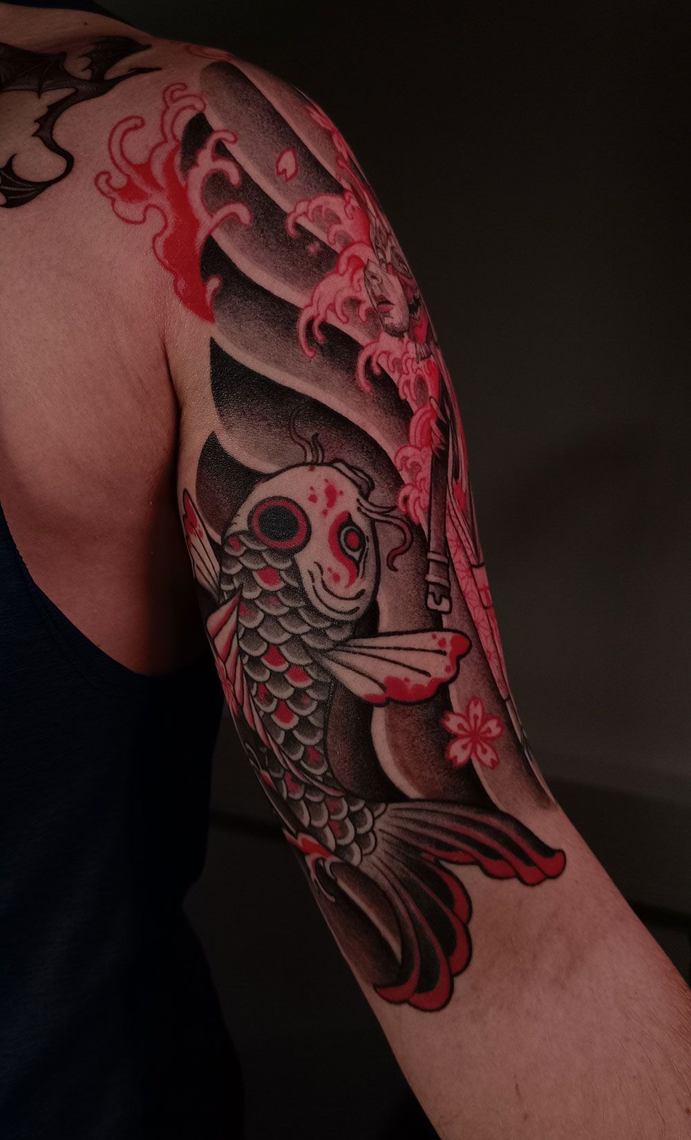 Eine Nahaufnahme des Arms einer Person mit einer Tätowierung eines Fisches und von Blumen.