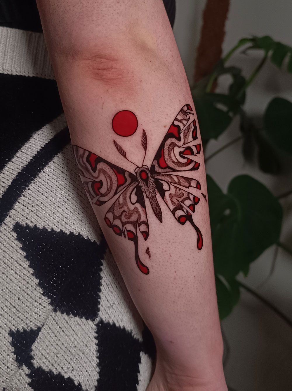 Eine Person hat eine Schmetterlingstätowierung auf dem Arm.