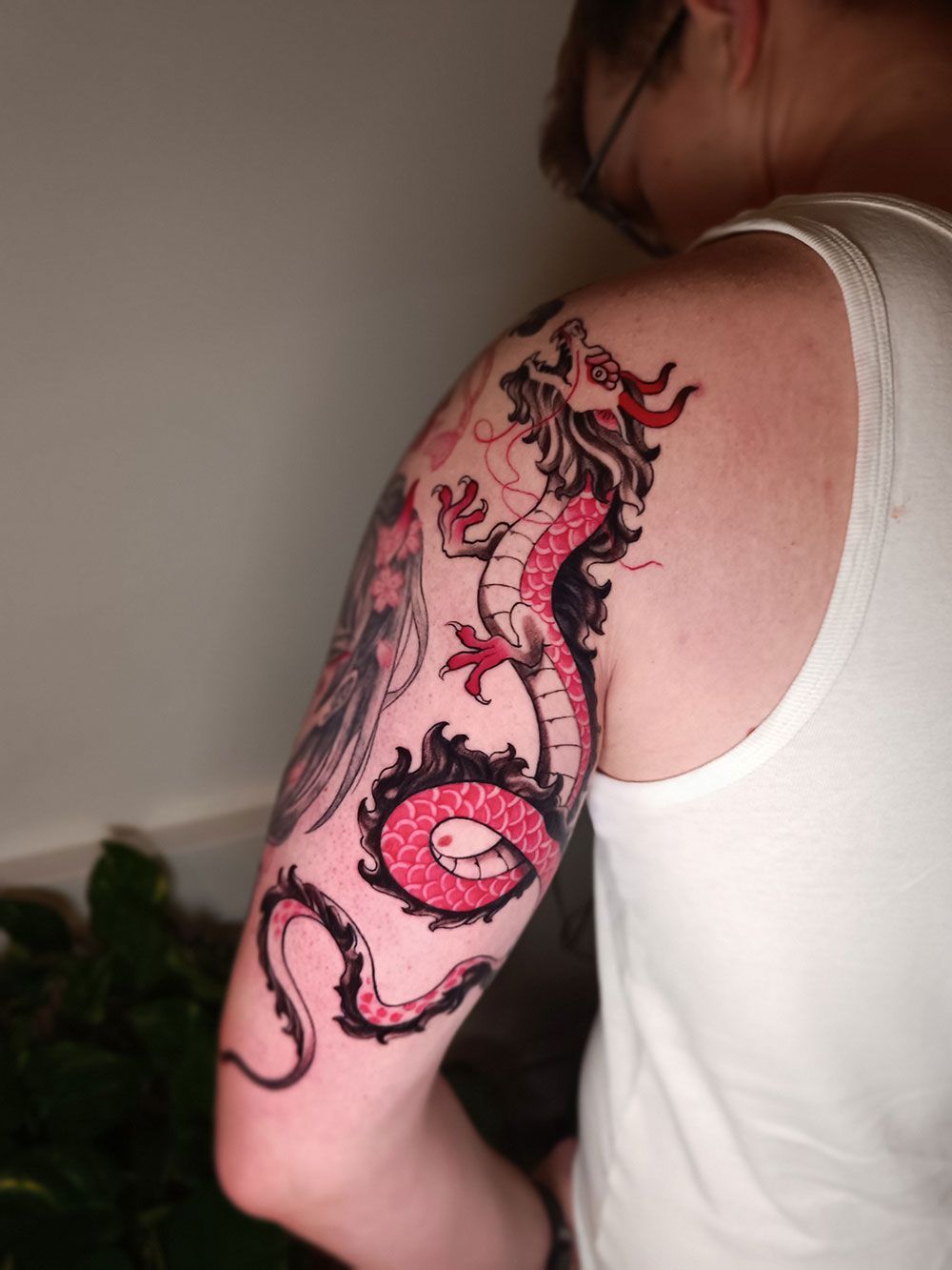 Eine Frau hat eine Tätowierung eines Drachen auf ihrem Arm