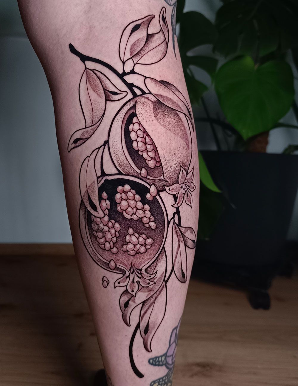 Eine Person hat eine Granatapfeltätowierung auf ihrem Bein.