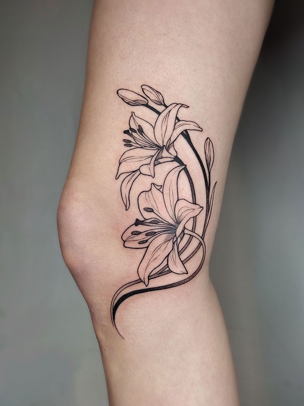 Ein schwarz-weißes Blumentattoo auf dem Bein einer Frau