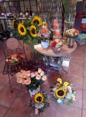 Ein Blumenladen mit verschiedenen Blumensträussen, darunter Sonnenblumen und Rosen, die auf einem Tisch und dem Boden ausgestellt sind.