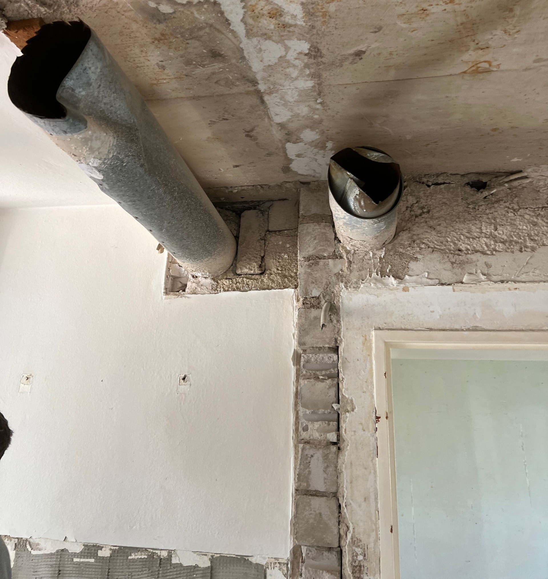 Kleines Badezimmer mit beigefarbenen Fliesenwänden, Toilette, Badewanne, Waschbecken und Fenster.