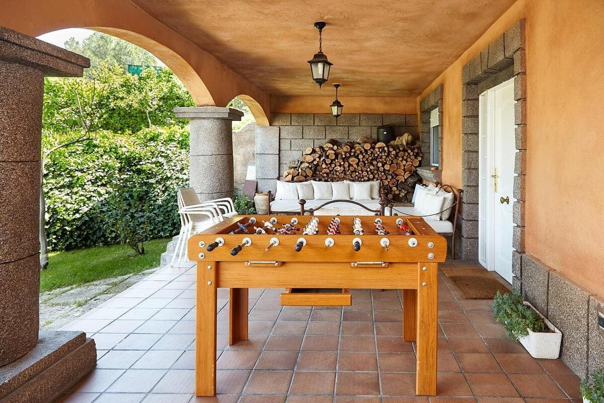 Hay una mesa de futbolín de madera en un patio al lado de un sofá.