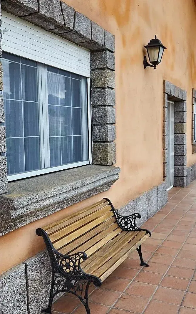 Un banco de madera está sentado frente a un edificio con una ventana.