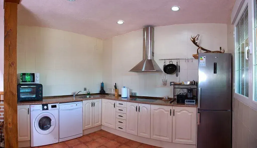 Una cocina con lavadora, lavavajillas, frigorífico y microondas.