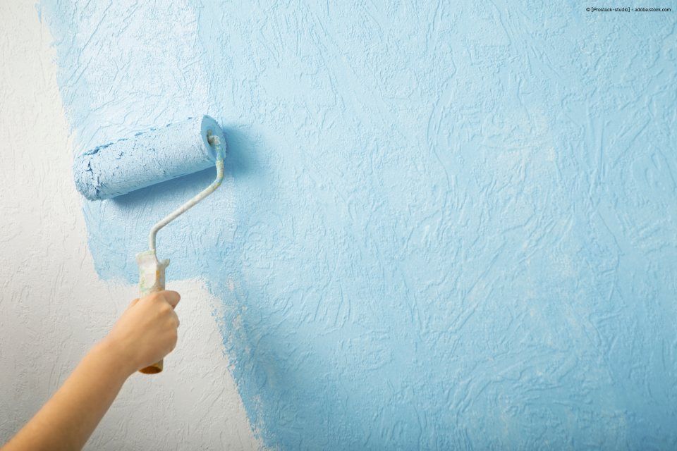 Hand, die mit Malerrolle Wand hellblau streicht, Malerfachbetrieb Schwarze