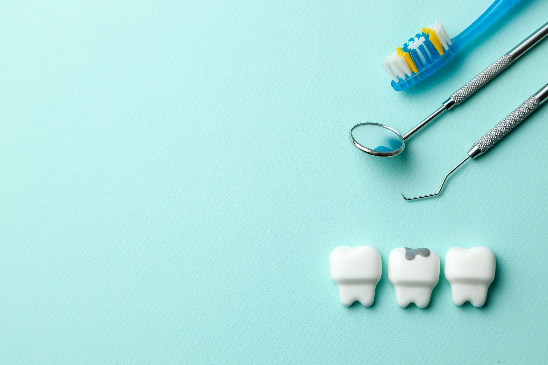 Brosse à dents, miroir dentaire, détartreur et trois modèles de dents sur fond vert menthe