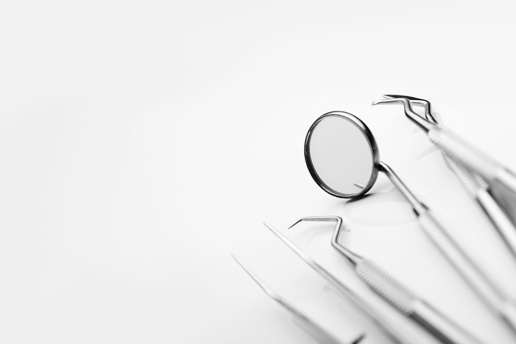 Outils dentaires et miroir sur fond blanc