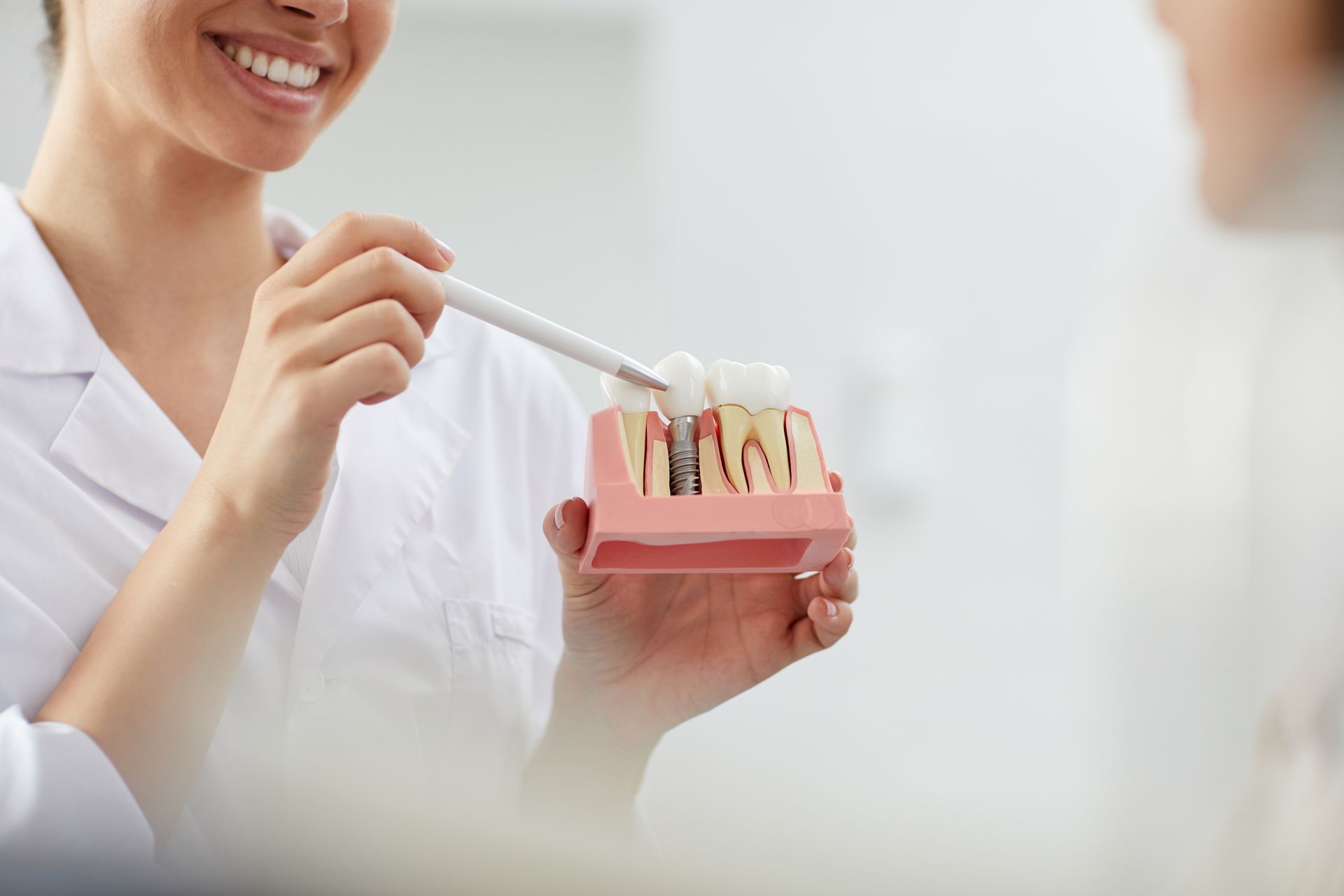 Un dentiste fait la démonstration des soins buccaux à l'aide d'un modèle de dents et d'une brosse à dents dans une clinique lumineuse.
