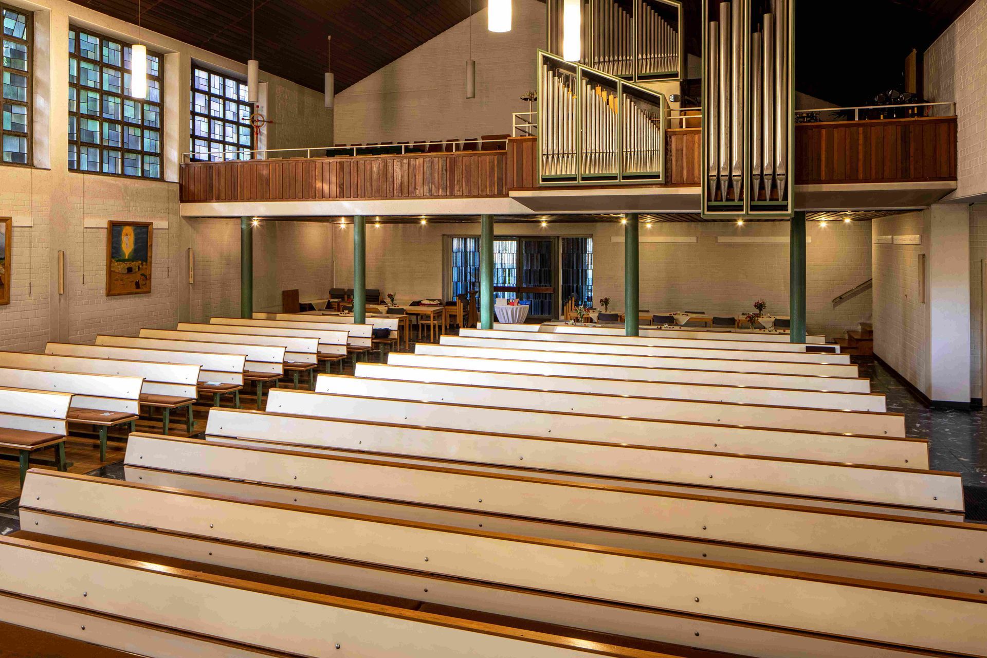 Der Innenraum einer Kirche. Zu sehen sind u.a. hellgraue Bankreihen, eine geschnitzte Kanzel und ein Altar mit Retabel.