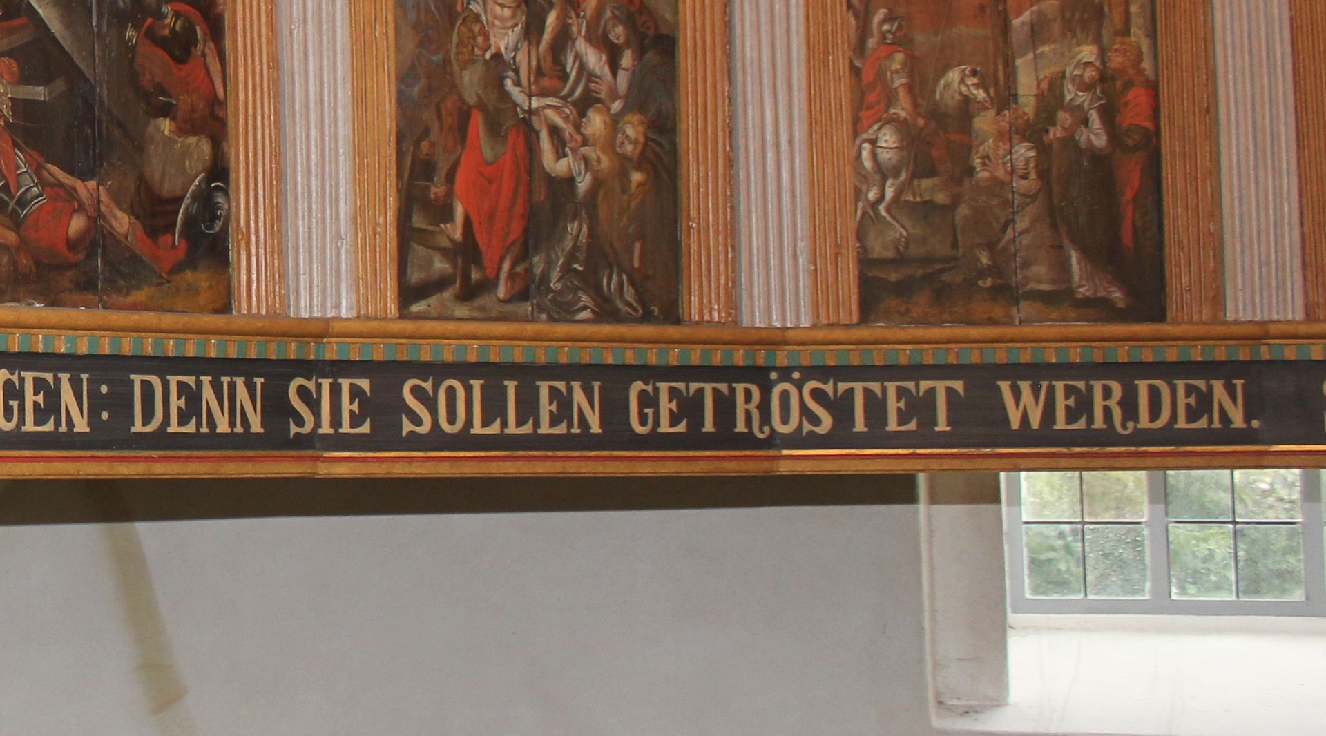 Auf einer Empore steht in Großbuchstaben: „Denn sie sollen getröstet werden.“
