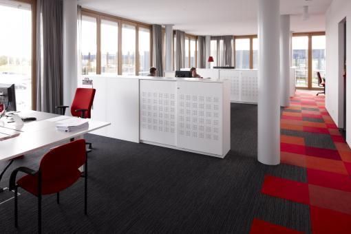 Una oficina grande con muchas ventanas y sillas rojas.