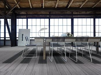 Un comedor con una mesa larga y sillas frente a un gran ventanal.