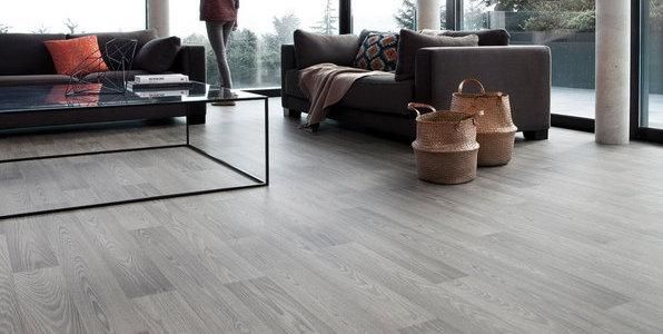 Una sala de estar con un sofá, una silla, una mesa de café y cestas en el suelo.