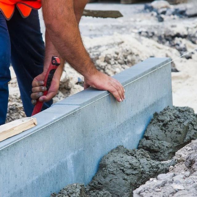 Un hombre está colocando hormigón sobre una pared de hormigón.