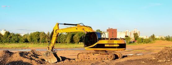 Una excavadora amarilla está moviendo tierra en un sitio de construcción.