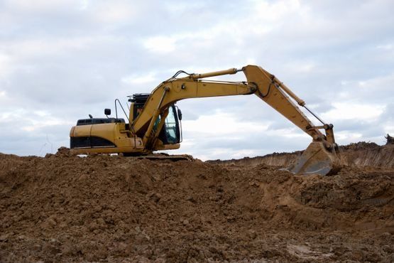 Una excavadora amarilla está cavando un hoyo en la tierra.