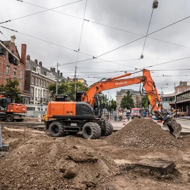 Una gran excavadora naranja está trabajando en un sitio de construcción.