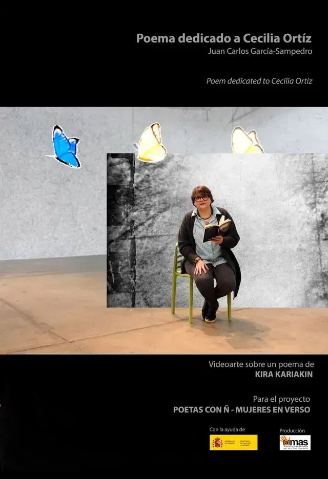 Una mujer de cabello oscuro y camisa blanca sonríe en un jardín con follaje verde y un camino.