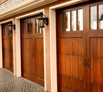 Una hilera de puertas de garaje de madera con linternas en el costado del edificio.