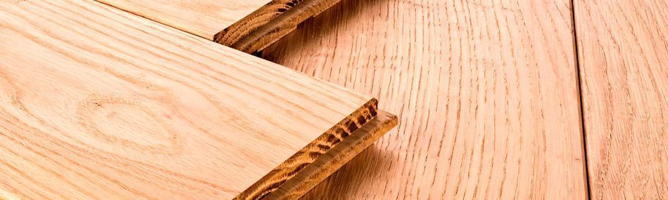 Un primer plano de una pila de tablas de madera sobre un piso de madera.