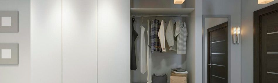 Un pasillo con un armario lleno de ropa y un espejo.