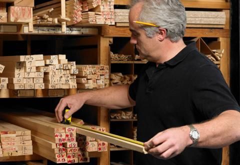 Un hombre está midiendo un trozo de madera en una tienda.