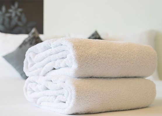 Dos toallas blancas están apiladas una encima de otra sobre una cama.