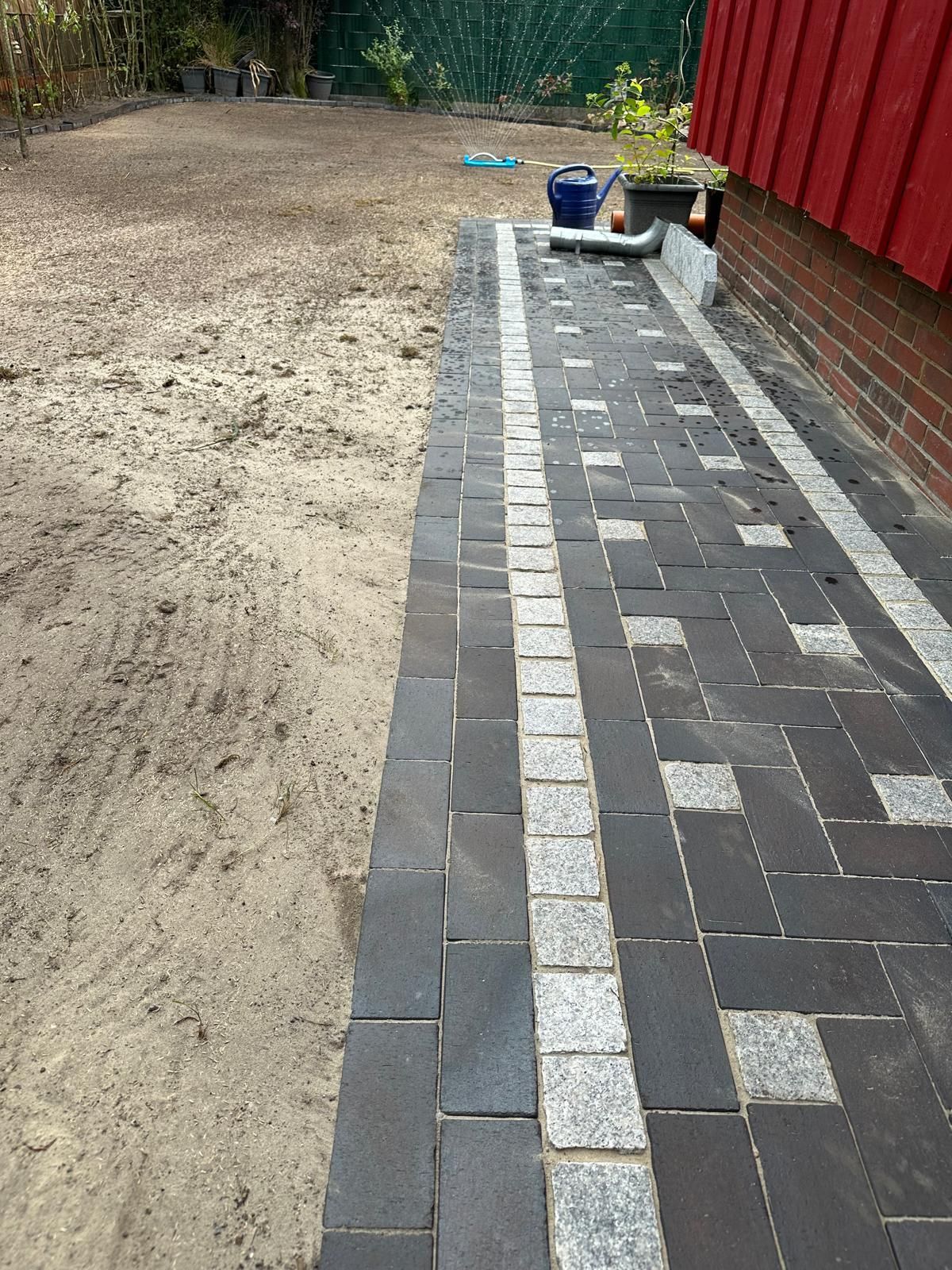 Ein Backsteinweg, der zu einem Feld neben einem Backsteingebäude führt.