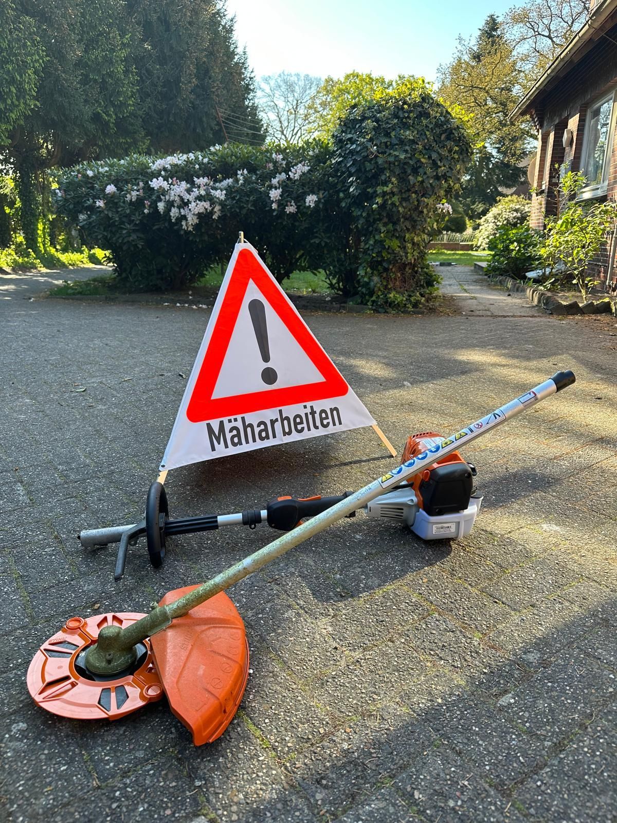 Ein Rasenmäher liegt neben einem Schild auf dem Boden.