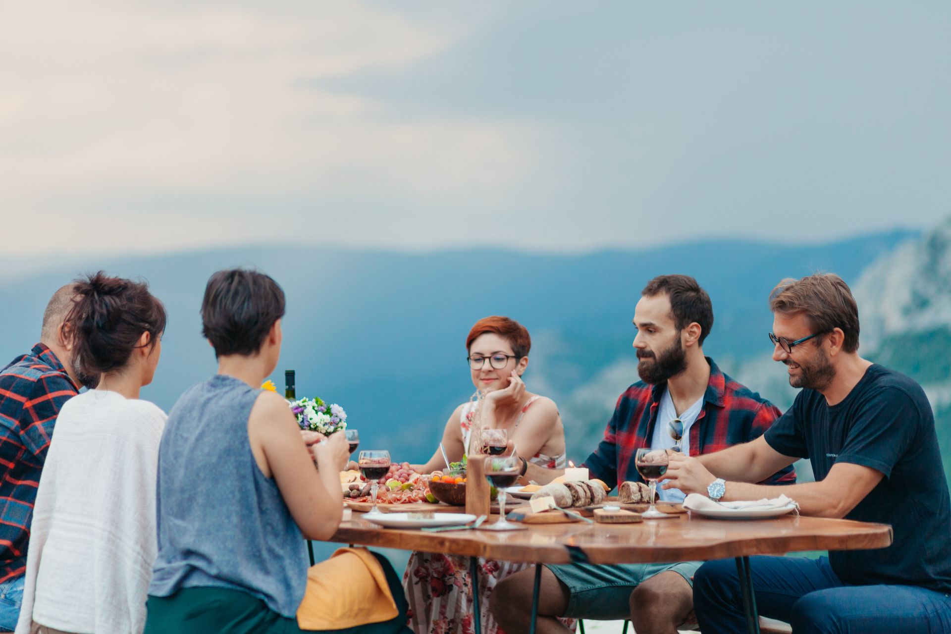 Amis mangeant sur une table avec en fond des montagnes