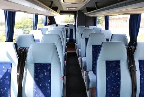 Das Innere eines Busses mit blauen Sitzen und blauen Vorhängen.