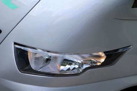 Eine Nahaufnahme eines Autoscheinwerfers auf einem weißen Auto.