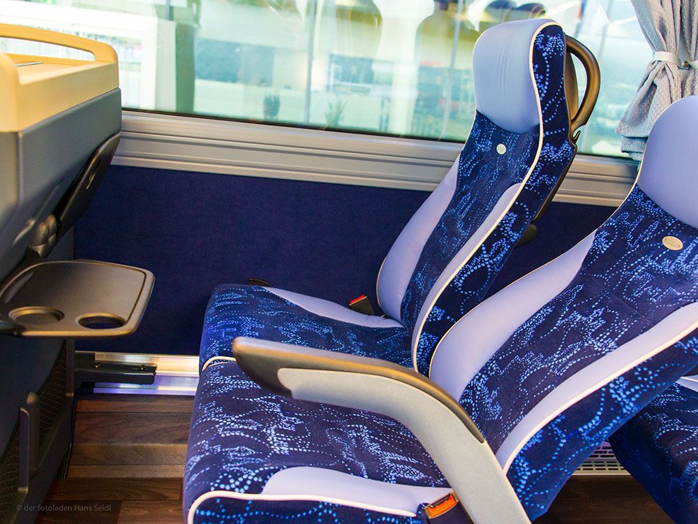 Blau-weiße Sitze in einem Bus mit einem Tisch darunter