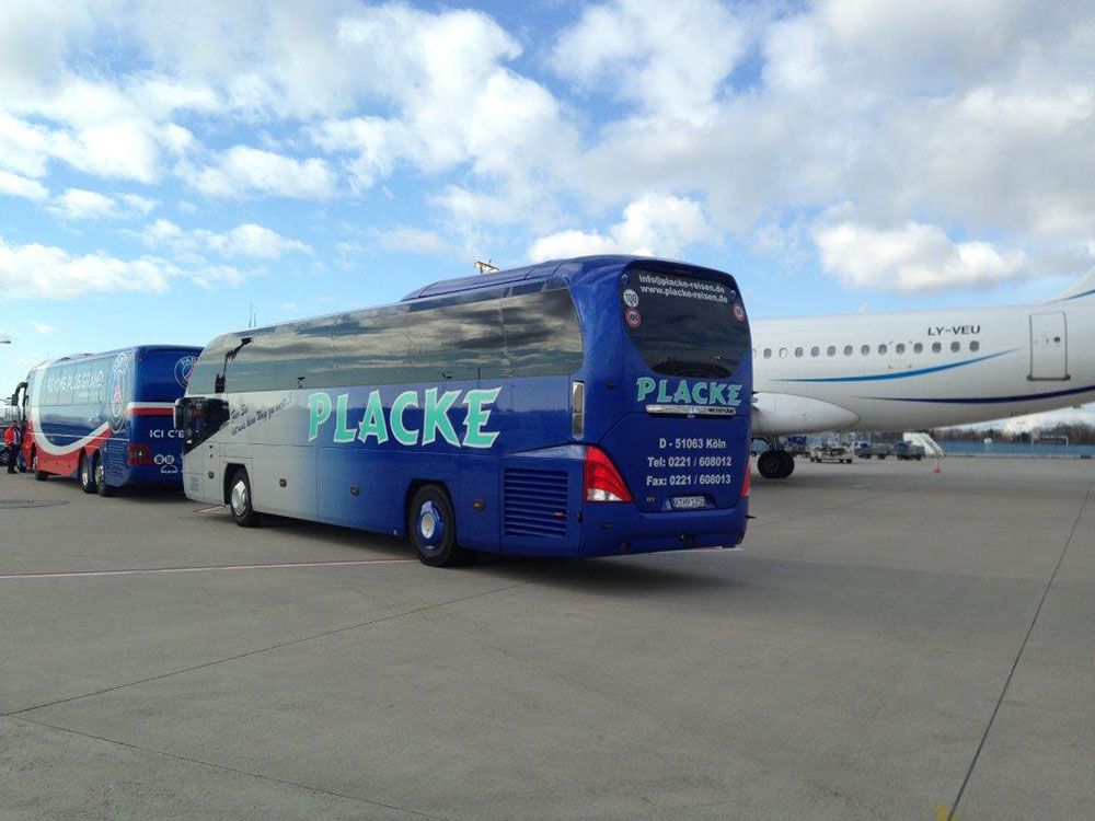 Ein blau gefleckter Bus steht vor einem Flugzeug