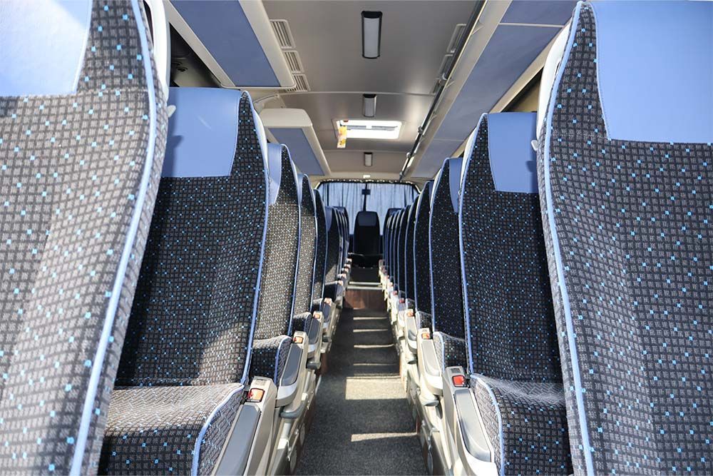 Das Innere eines Busses mit blauen Sitzen und einer Deckenleuchte