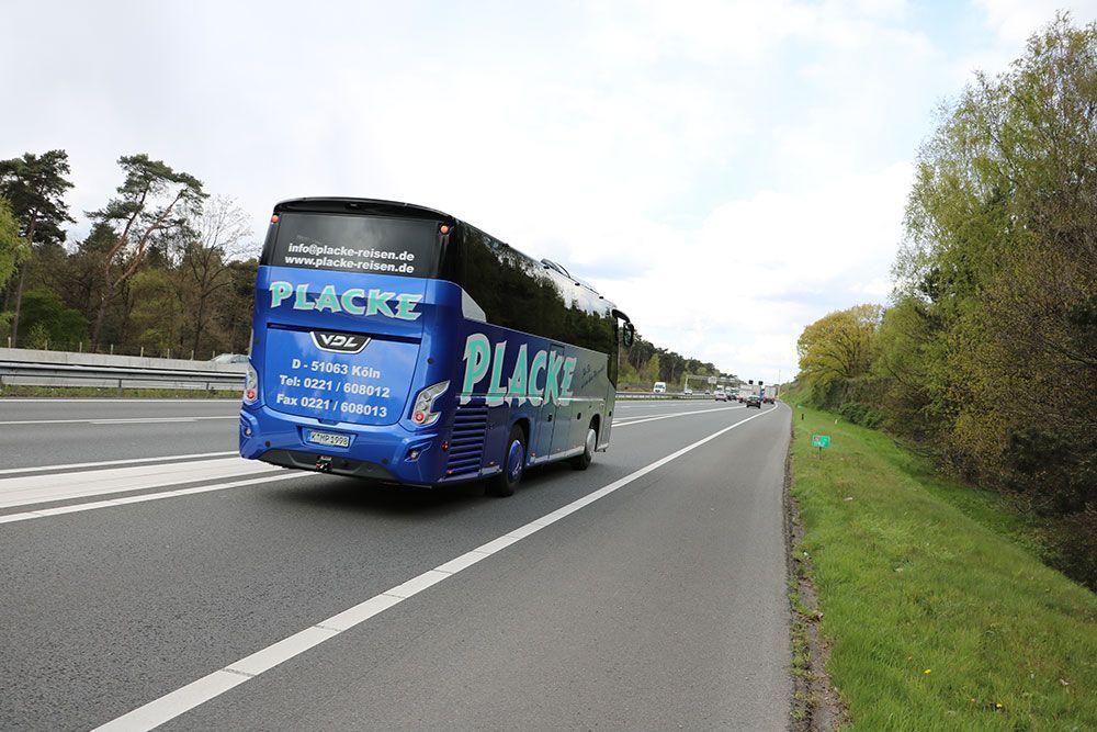 Ein blauer Bus fährt eine Autobahn entlang